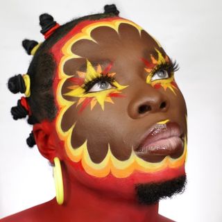 A woman with colorful face paint and dreadlocks.