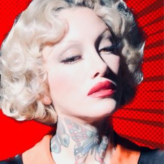 A woman with tattoos and blond hair in front of a red background.
