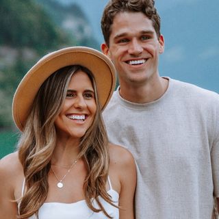 A man and woman smiling in front of a lake.