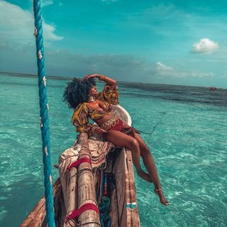 A woman sitting on the back of a boat in the ocean.