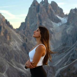 A woman standing on top of a mountain in the dolomites.
