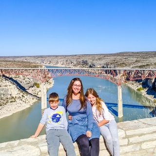 A family posing for a photo in front of a bridge.