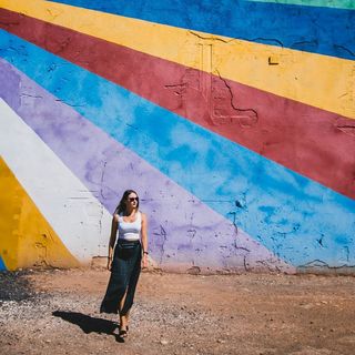 brunette influencer standing before a colorful wall 