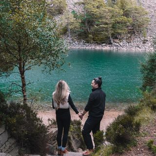 couple influencers holding hands in front of a lac.