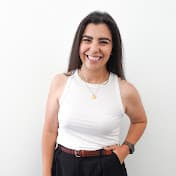 A smiling woman in a white tank top and black pants.