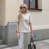 A woman in a white top and pants is walking down the street.