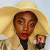 A woman in a yellow hat posing for a photo.