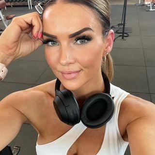 A woman wearing headphones posing in a gym.