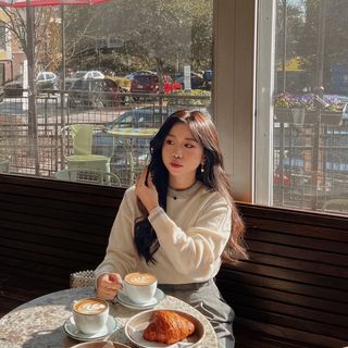 A woman sitting at a table with a cup of coffee.