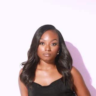 A black woman in a black dress posing for a photo.