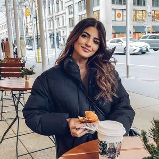 A woman sitting at a table with a cup of coffee and a donut.