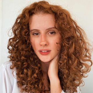 A woman with curly red hair posing for a photo.