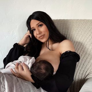 A woman is breastfeeding her baby in a chair.