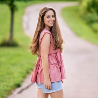 A young woman wearing a pink top and denim shorts.