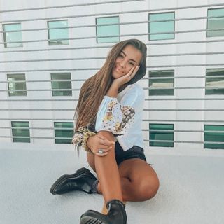 A young woman sitting on the ledge of a building.