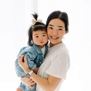 A woman holding a baby in a white room.