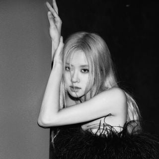 A black and white photo of a woman leaning against a wall.