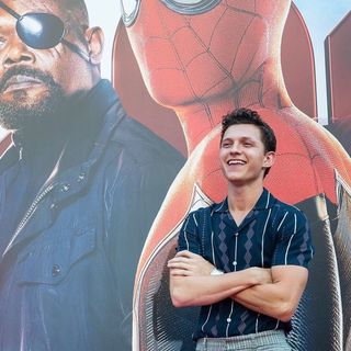 A man standing in front of a spider - man poster.