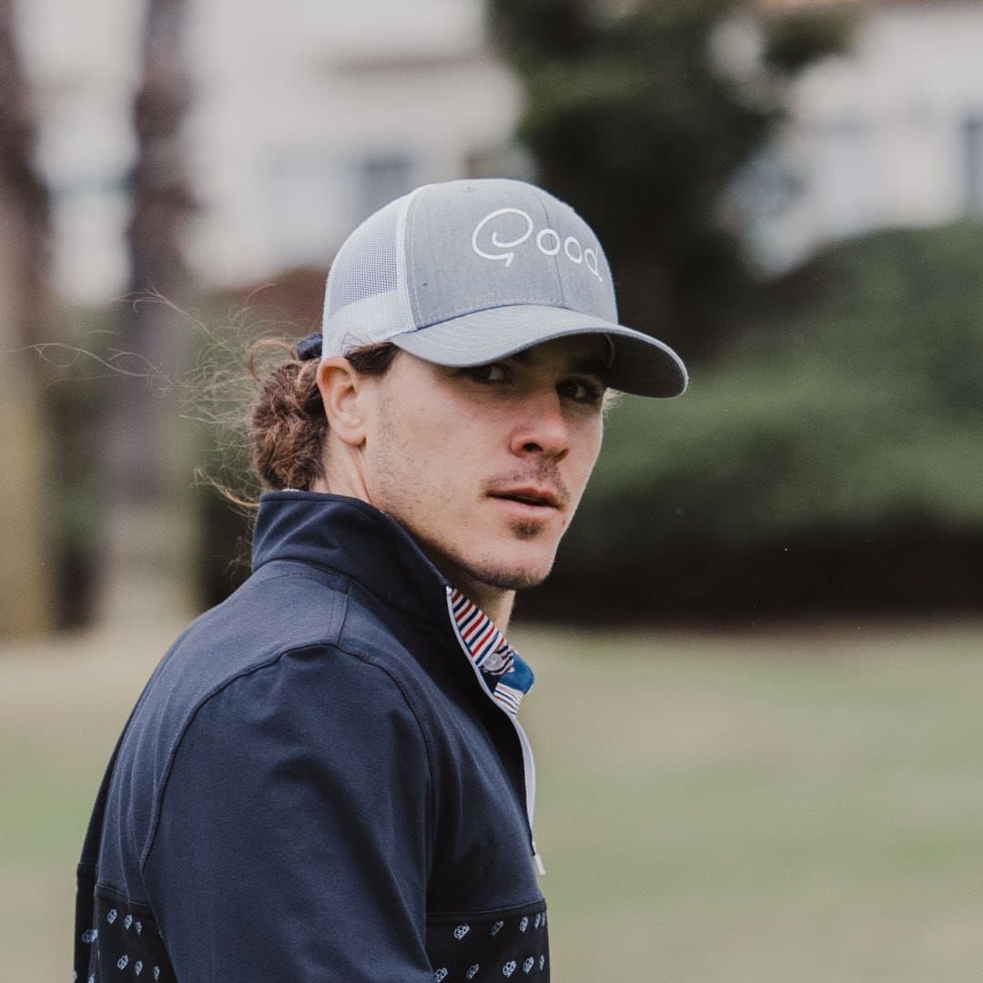 A man wearing a hat and a jacket on a golf course.