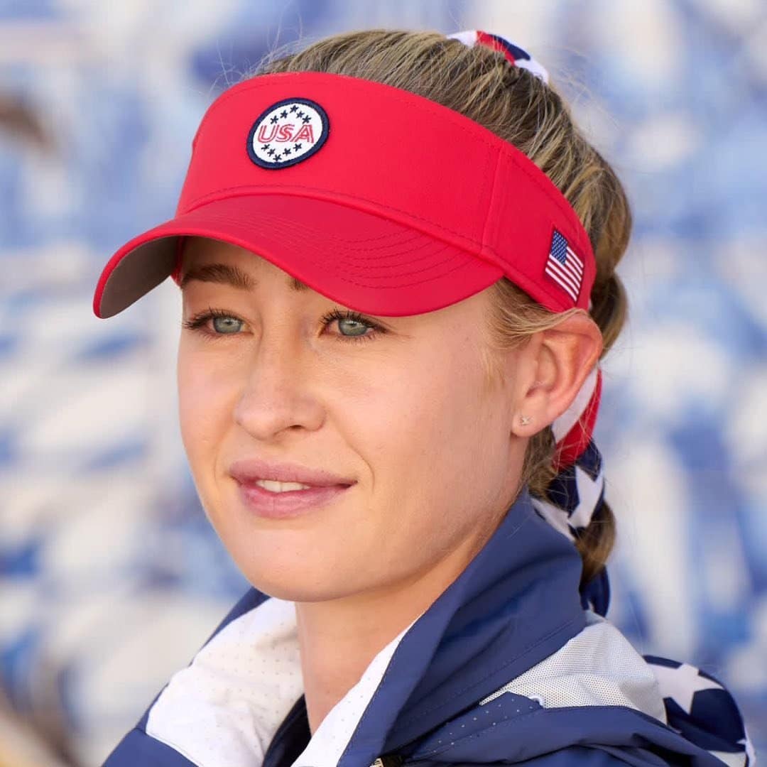 A woman wearing a red visor with an american flag on it.