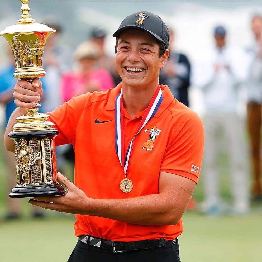 A golfer holding up a trophy in front of a crowd.