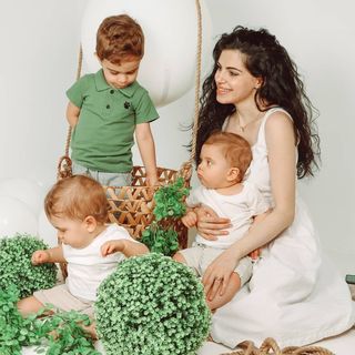 A woman with two children sitting on the floor.