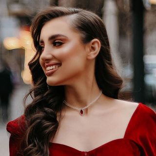 A woman in a red velvet dress smiles on the street.