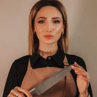 A woman in an apron holding a knife.