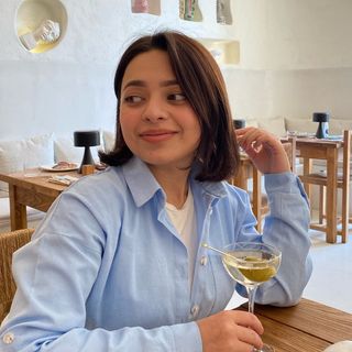 A woman sitting at a table with a glass of wine.