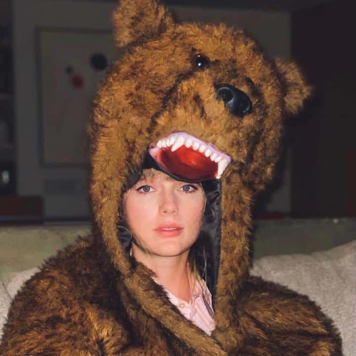 A woman in a bear costume sitting on a couch.