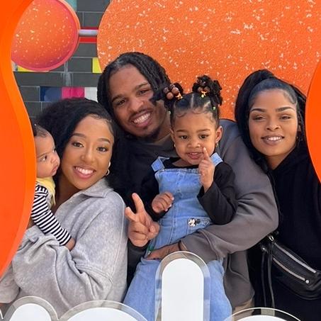 A family posing for a picture in front of an orange sign.