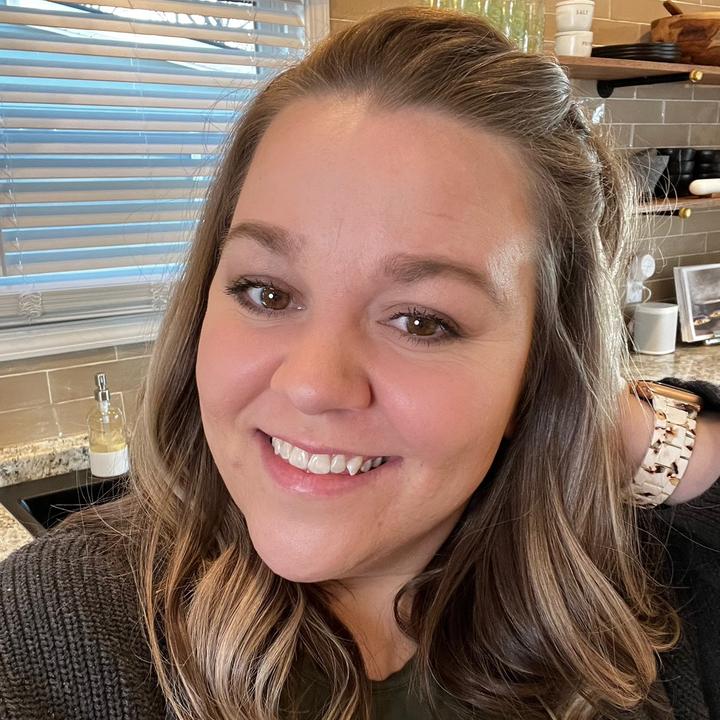 A woman smiles while sitting in a kitchen.