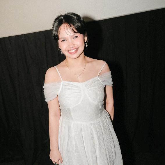 A young woman in a white dress posing for a photo.