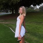 A woman in a white dress standing on a golf course.