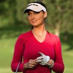 A woman in a red shirt holding a golf club.