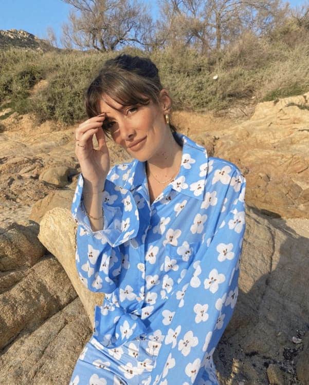 A woman in blue floral pajamas sitting on rocks.