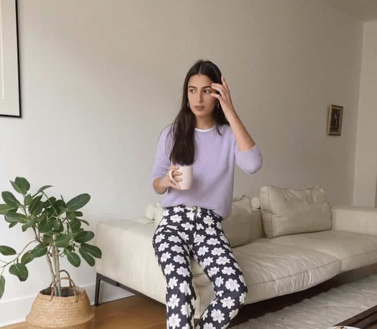 A woman is sitting on a couch with a cup of coffee.