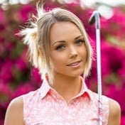 A young woman in a pink shirt holding a golf club.