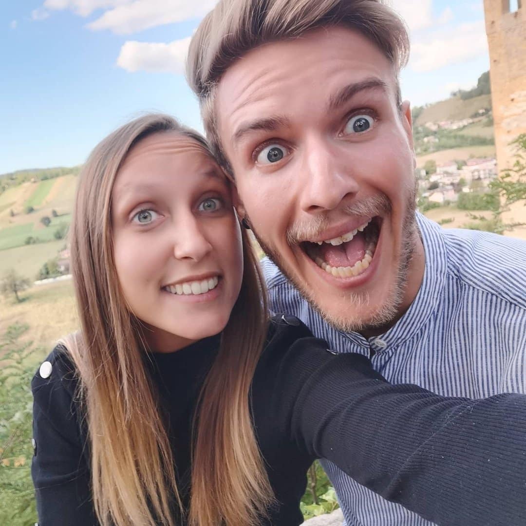 A man and woman taking a selfie in front of a castle.