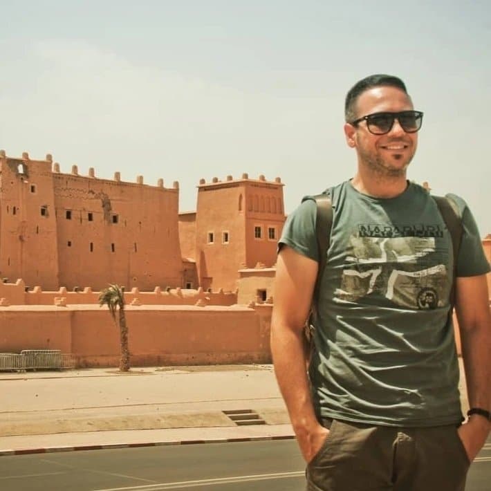 A man standing in front of an old building in morocco.