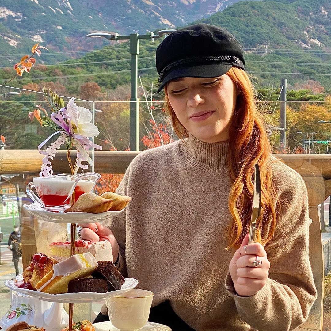 A woman sitting at a table with a tray full of desserts.