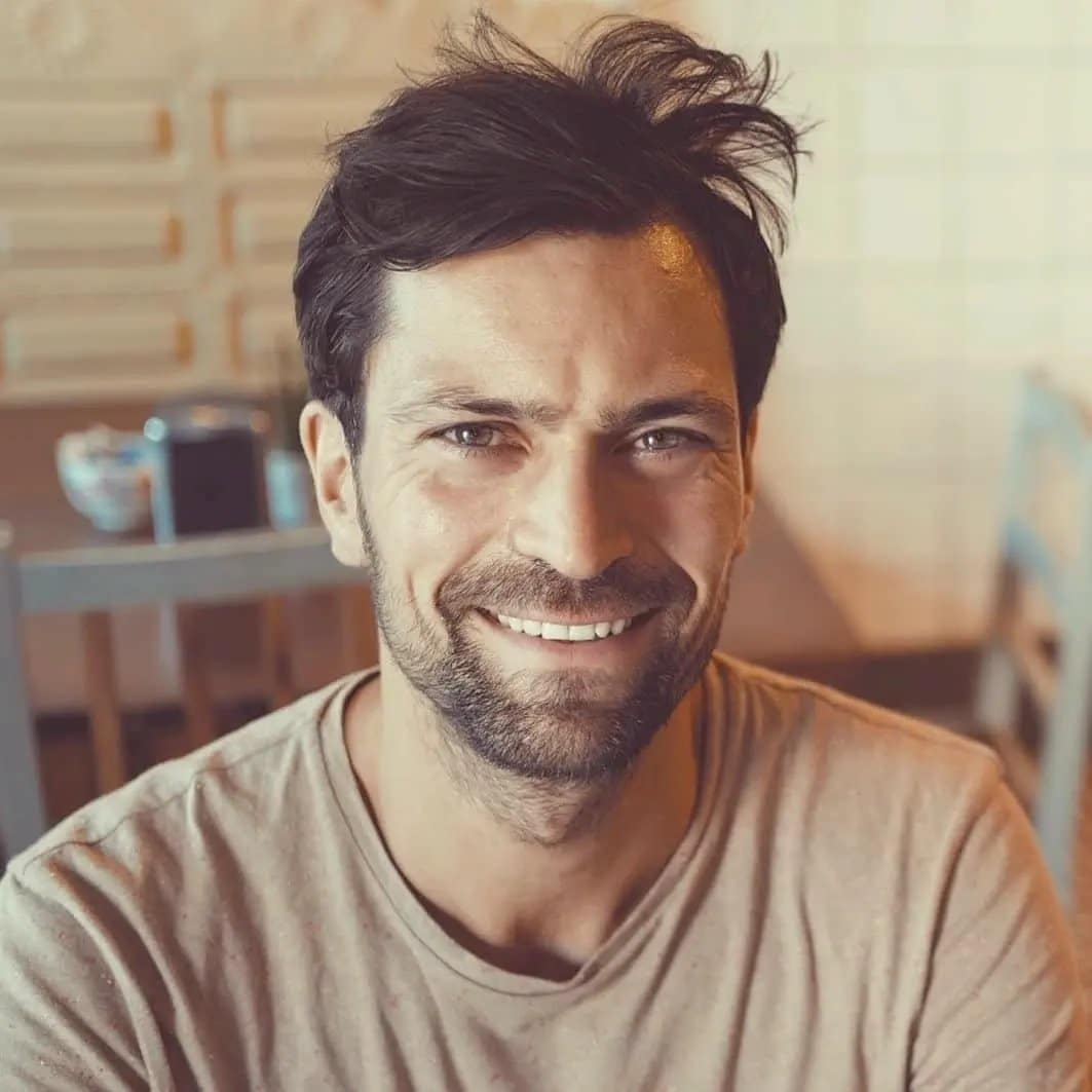 A man smiling at a table in a restaurant.