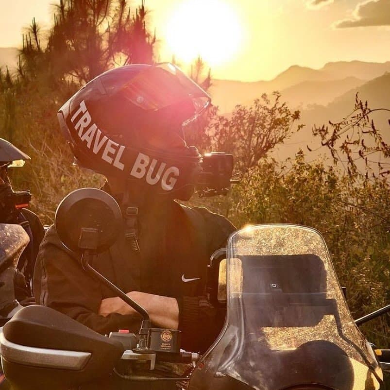Two people riding motorcycles in the mountains at sunset.