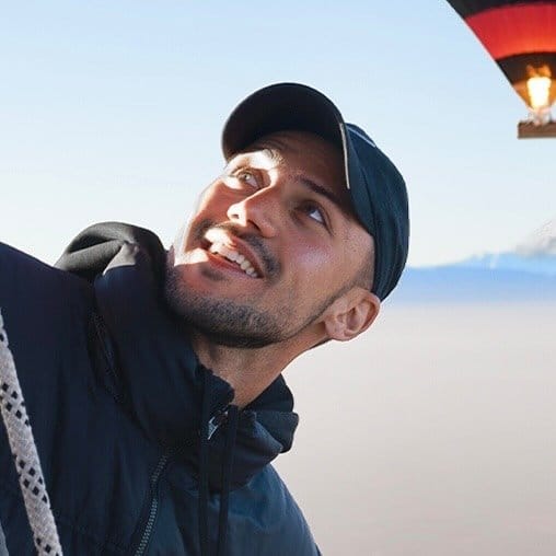 A man holding a hot air balloon in the sky.