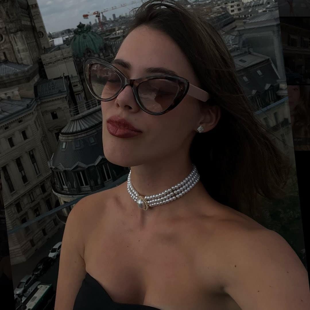 A woman wearing glasses and a choker on top of a building.