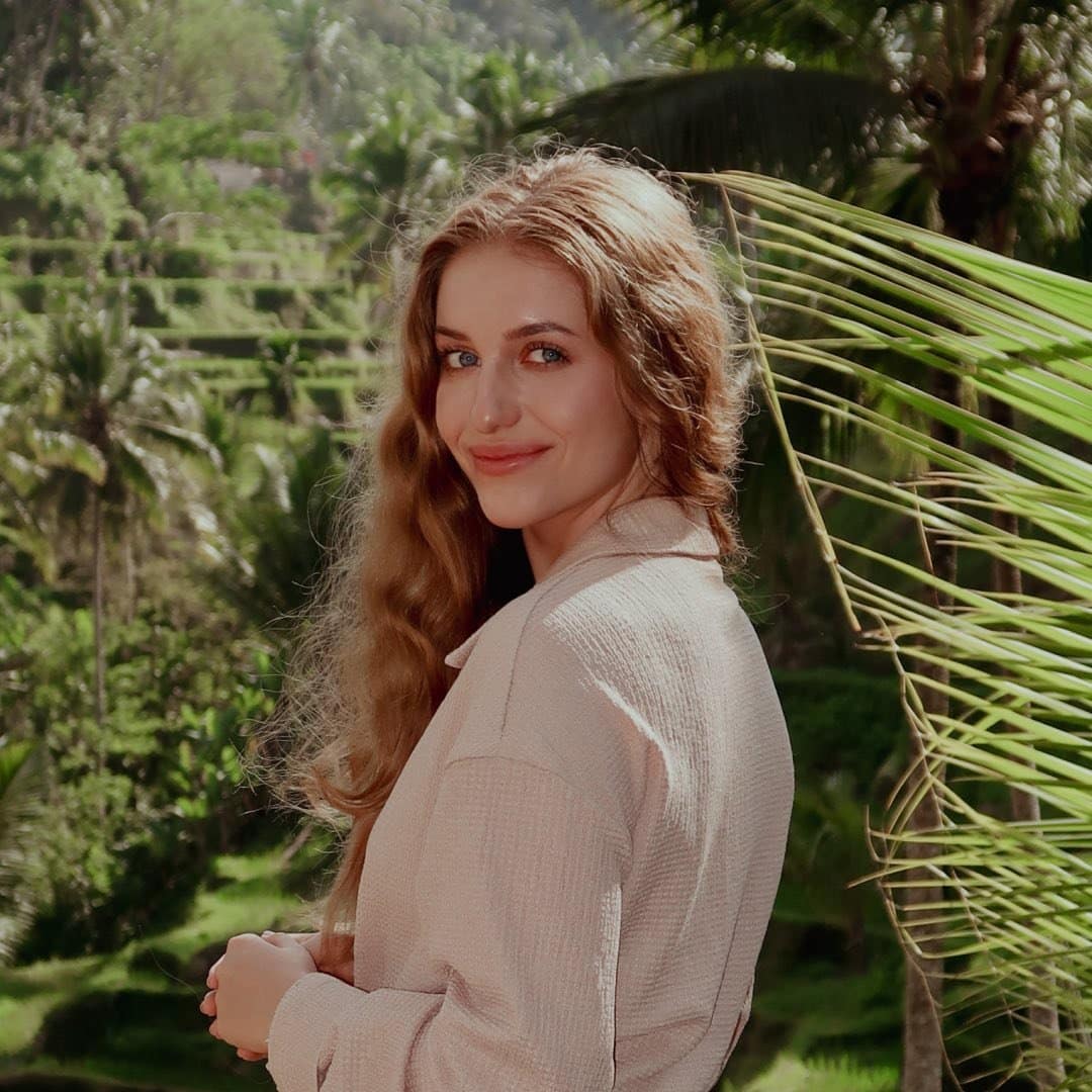 A woman is standing in front of a rice terrace.