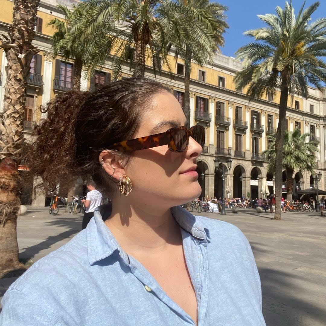 A woman wearing sunglasses in front of a palm tree.