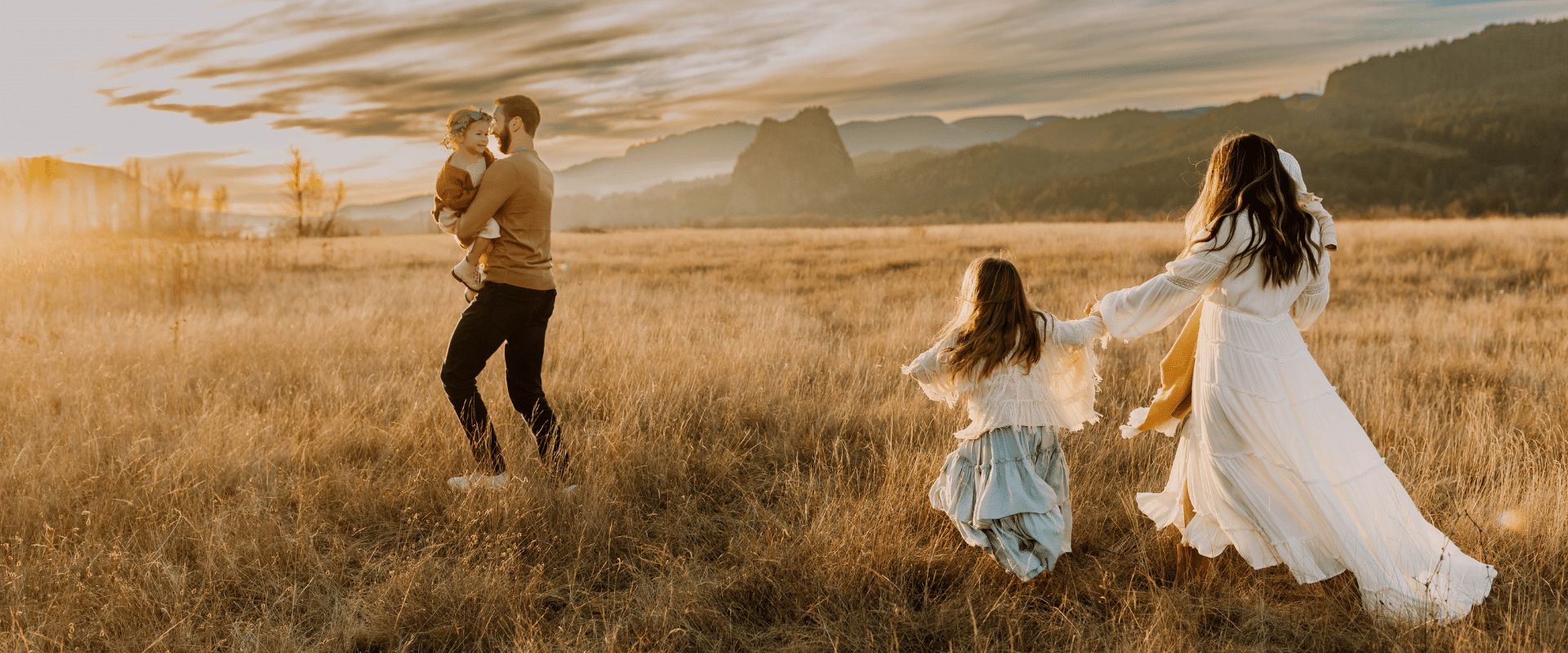 A family walks through a field at sunset.