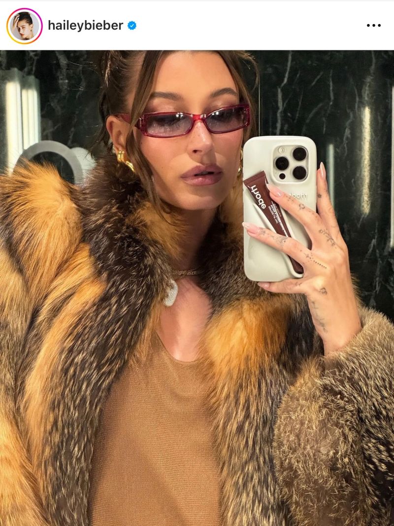 A woman is taking a selfie in a fur coat.