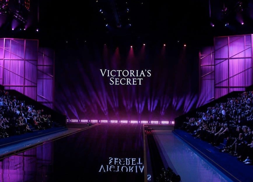 Victoria Secret 2025: The Comeback 1 A runway stage with purple lighting and a large